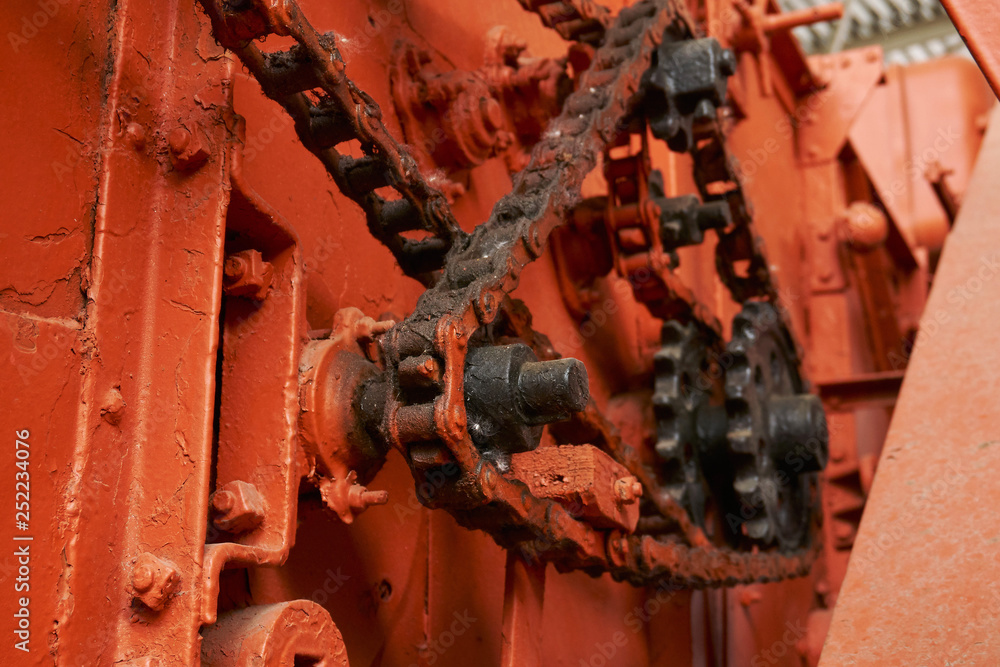 high-quality metal gears and chains on an old tractor of bright orange color in the museum of agricultural equipment high-quality metal gears and chains on an old tractor of bright orange color in the museum of agricultural equipment
