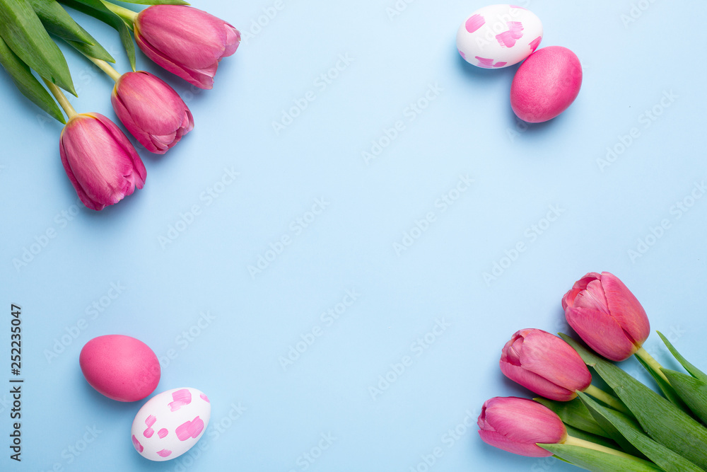 Pink flowers tulips and easter eggs on a blue background