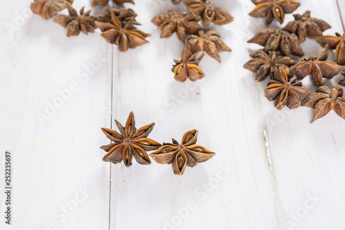 Group of two whole dry brown star anise fruit in a focus on white wood
