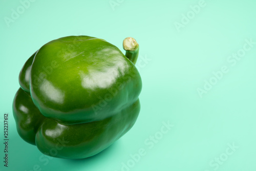 fresh green bell pepper on a light green background with copy space