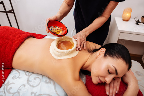 Obraz na płótnie Dark-haired relaxed woman experiencing Ayurveda treatment in salon