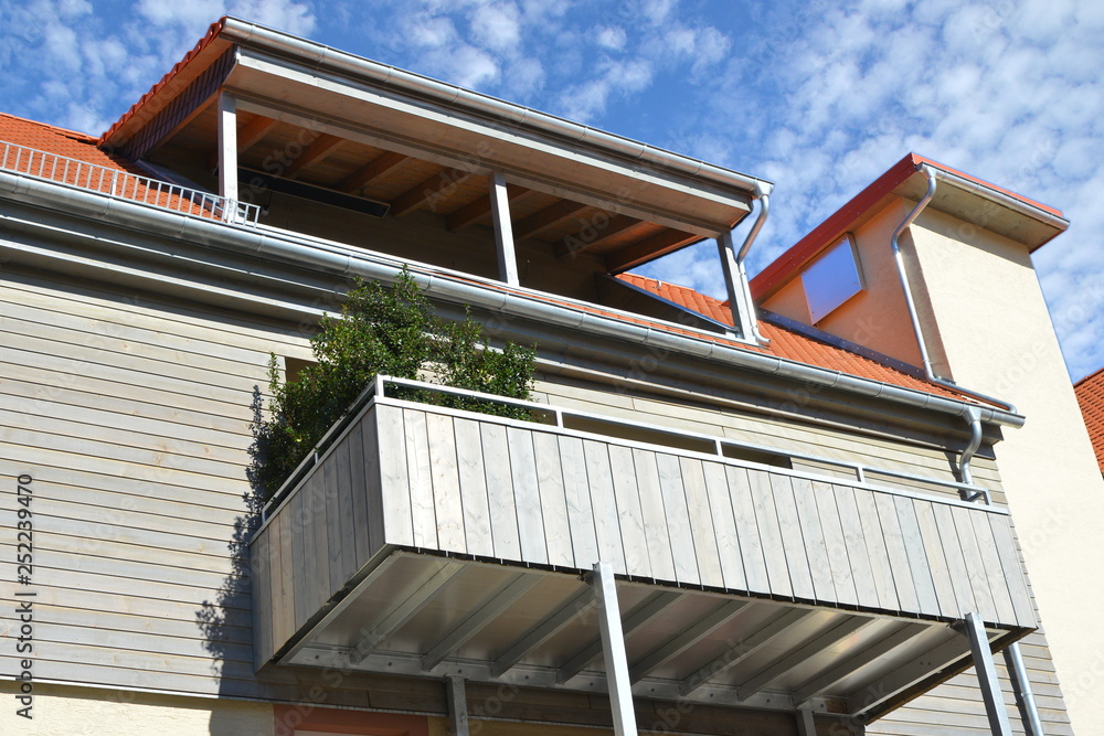 Überdachter Dachbalkon und Balkon mit Metall-Geländer und und Sichtschutz  aus lasiertenten Holzplanken an einem Wohnhaus Stock Photo | Adobe Stock