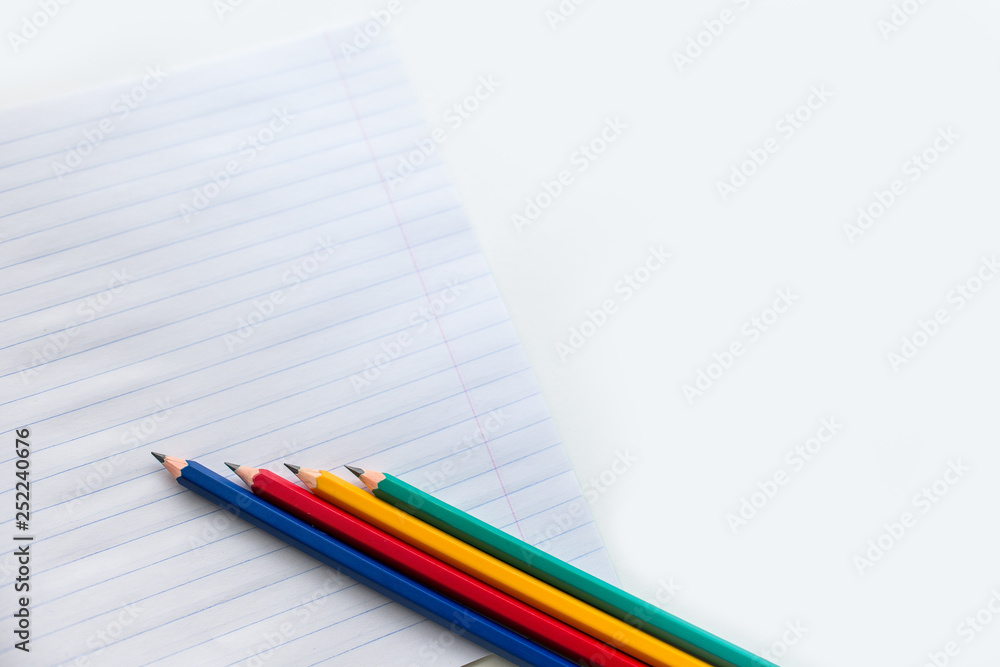 Multicolored pencils on notebook in a ruler Multicolored pencils on notebook in a ruler