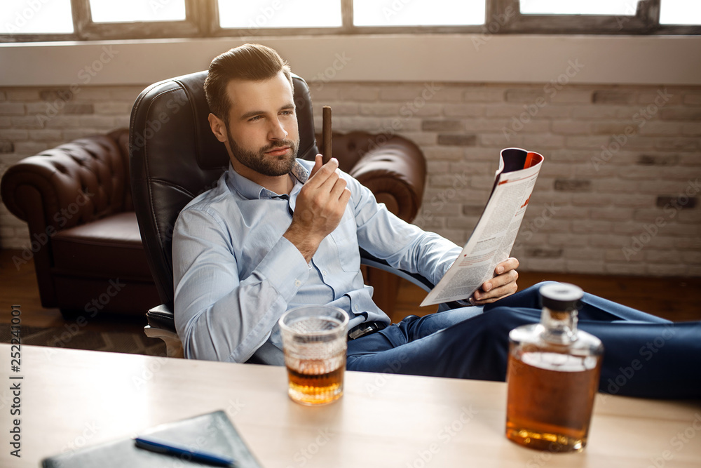 Focused man sipping alcoholic beverage while thinking about next chess move.  Stock Photo by DC_Studio