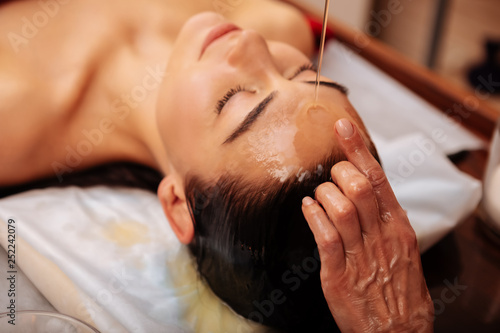 Dark-haired sleepy woman feeling meditative during procedure