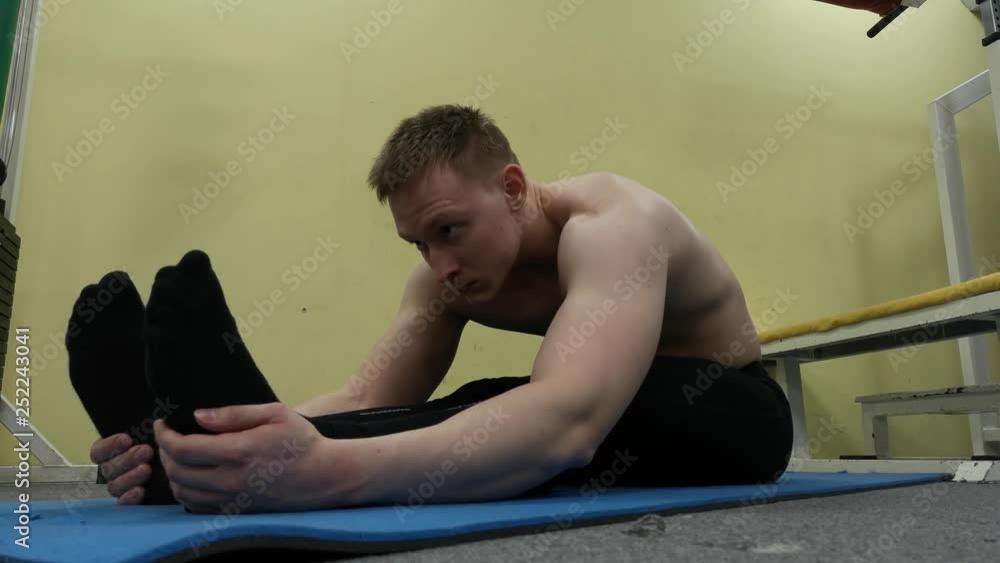Sporty man stretching arm before gym workout. Fitness strong male athlete standing indoor warming up Sporty man stretching arm before gym workout. Fitness strong male athlete standing indoor warming up