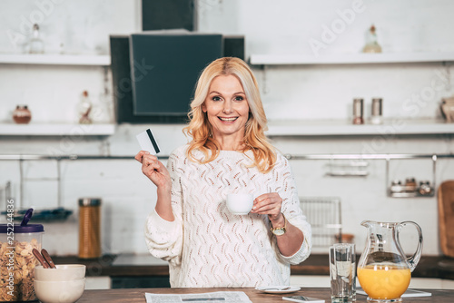 attractive blonde woman holding credit card and cup in hands © LIGHTFIELD STUDIOS