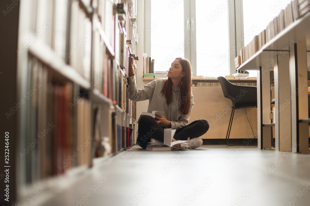 Young student in library reading a book Young student in library reading a book