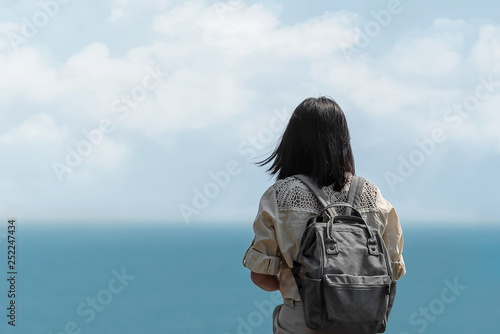 Solo Asian beautiful girl backpack traveller standing alone and looking the sea ,enjoy her vacation feel freedom and fresh air,Freedom lifestyle concept