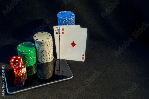 Selection of gambling items, poker chips, dice, Playing cards, with a mobile phone, online gambling