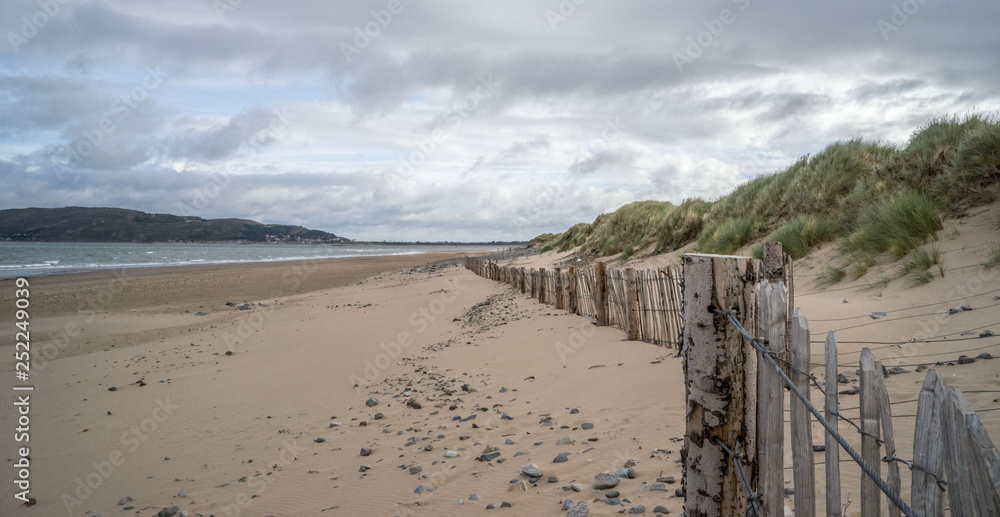 Deserted sandy beach with fence and dune