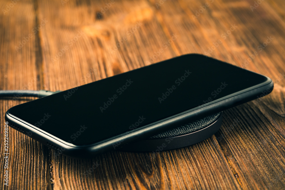 Charge your smartphone on the charging pad. Wireless charging on wooden table. rendered image. Charge your smartphone on the charging pad. Wireless charging on wooden table. rendered image.