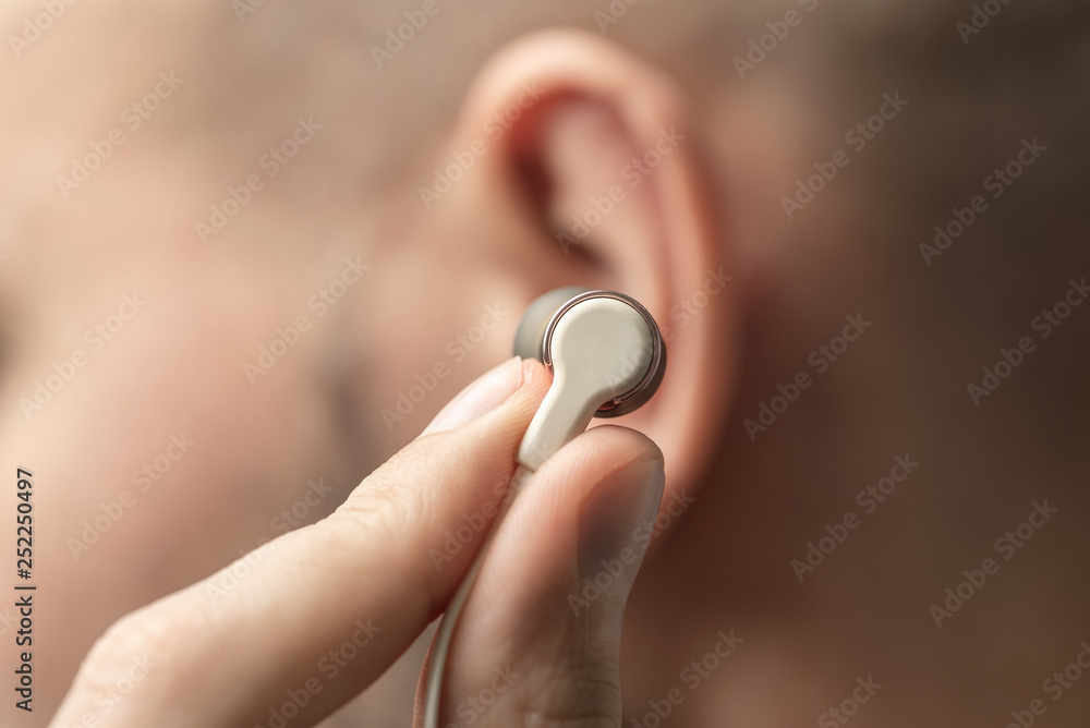 A small earphone in the male hand near the ear A small earphone in the male hand near the ear