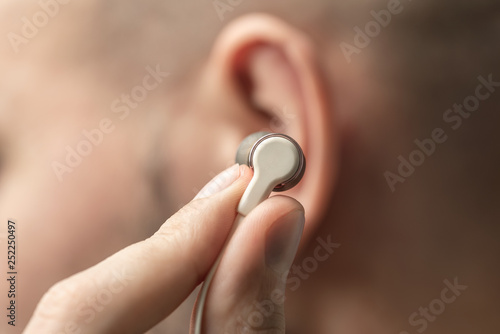 A small earphone in the male hand near the ear