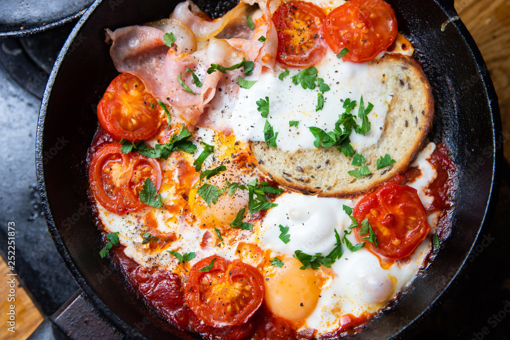 Fried eggs with bacon, toast and tomatoes in a pan Fried eggs with bacon, toast and tomatoes in a pan