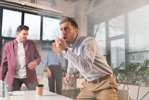 terrified businessman standing with open mouth near colleagues in office with smoke © LIGHTFIELD STUDIOS