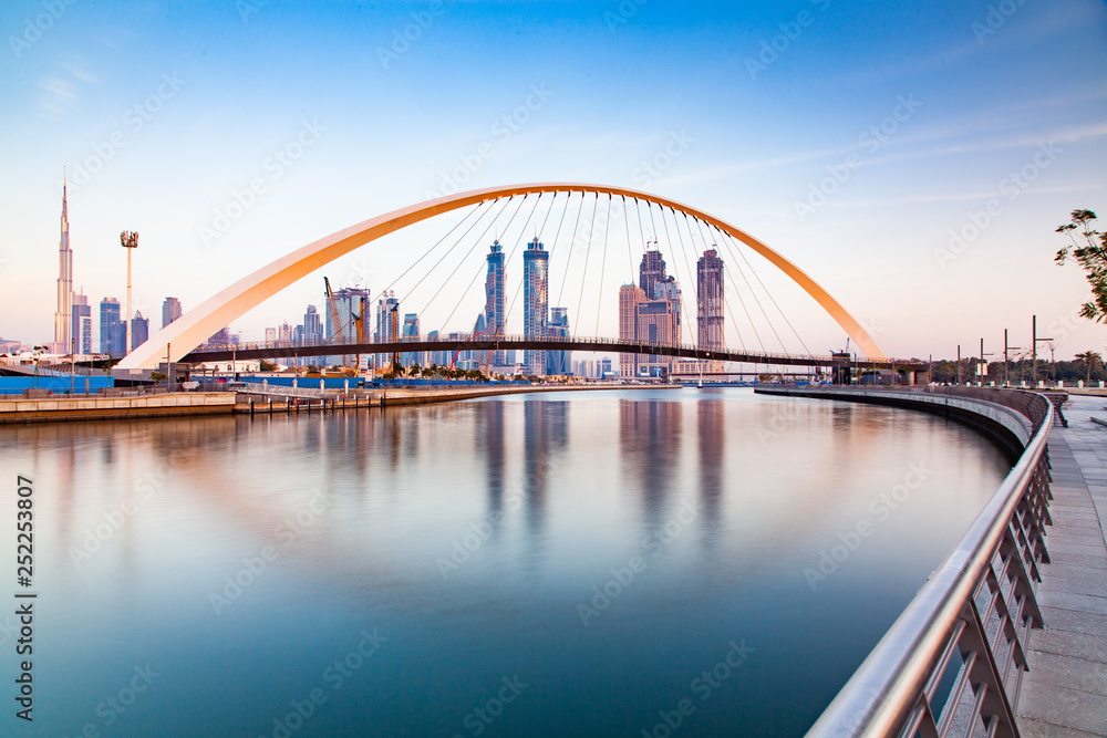 Naklejka premium kolorowy zachód słońca nad drapaczami chmur w centrum Dubaju i nowo wybudowanym mostem Tolerance, patrząc z kanału wodnego w Dubaju