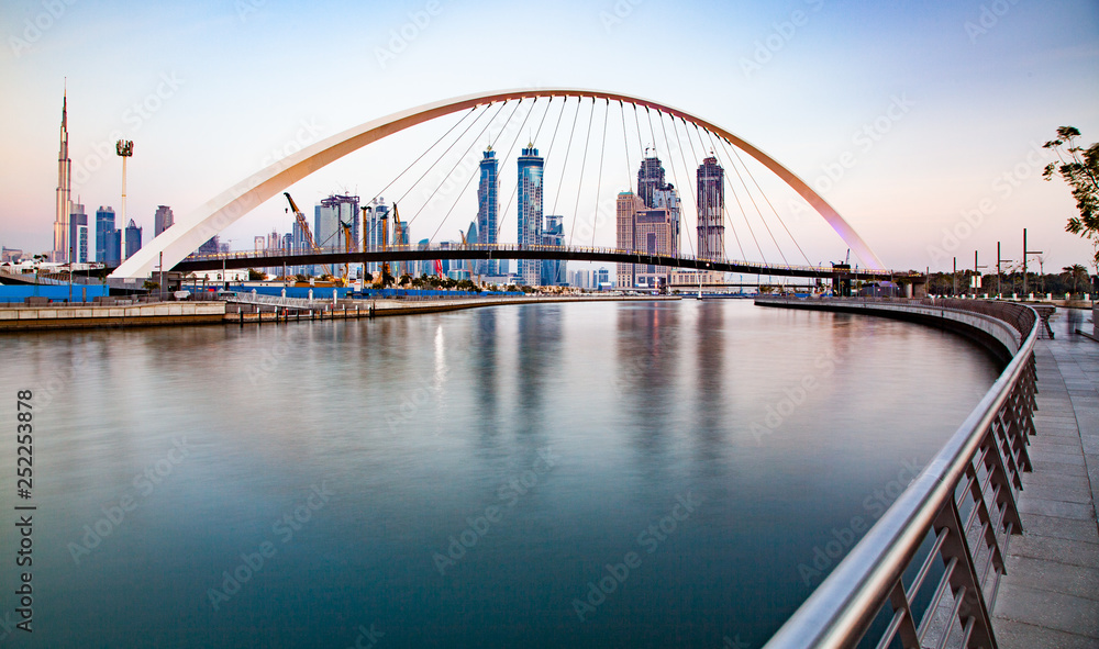 Naklejka premium colorful sunset over Dubai Downtown skyscrapers and the newly built Tolerance bridge as viewed from the Dubai water canal