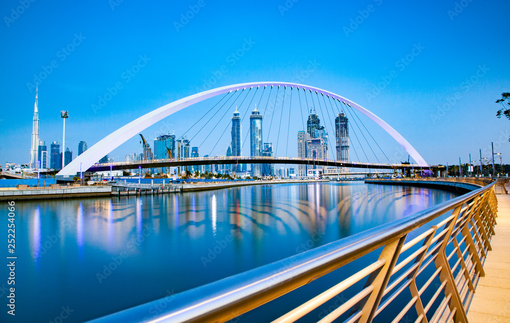 colorful sunset over Dubai Downtown skyscrapers and the newly built Tolerance bridge as viewed from the Dubai water canal