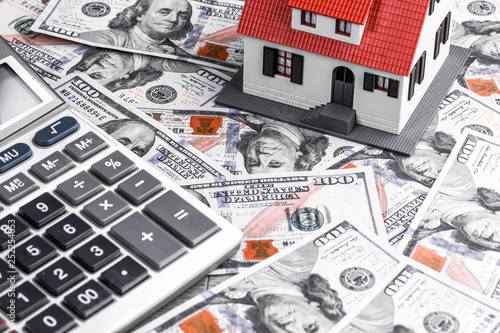 Close-up of a house model with calculator on dollar notes. Mortgage concept