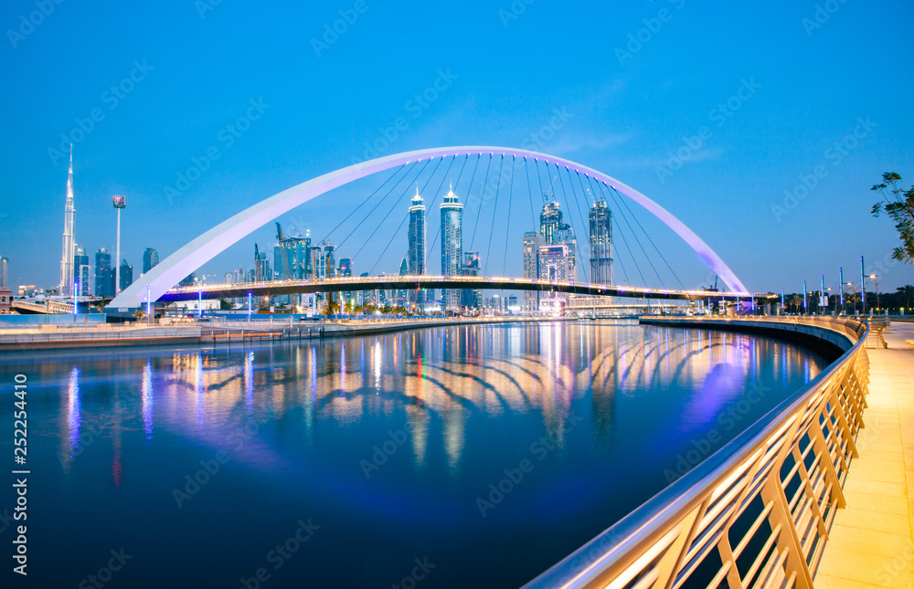 Naklejka premium kolorowy zachód słońca nad drapaczami chmur w centrum Dubaju i nowo wybudowanym mostem Tolerance, patrząc z kanału wodnego w Dubaju