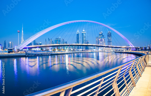 colorful sunset over Dubai Downtown skyscrapers and the newly built Tolerance bridge as viewed from the Dubai water canal