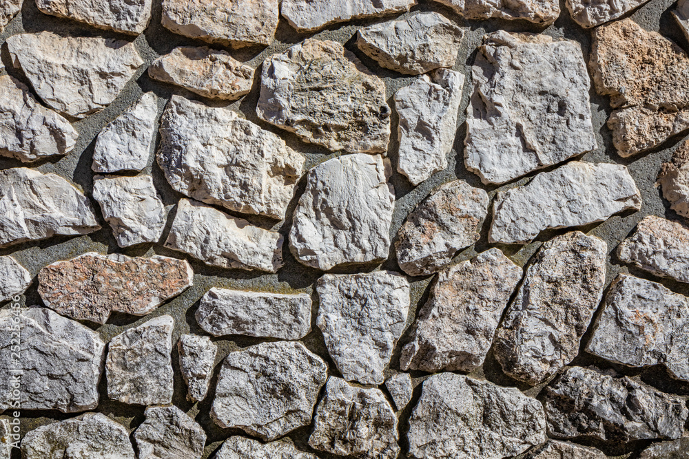 Fototapeta premium Wall made of cement and irregularly shaped stones. Architectural detail, closeup. Texture, material background.