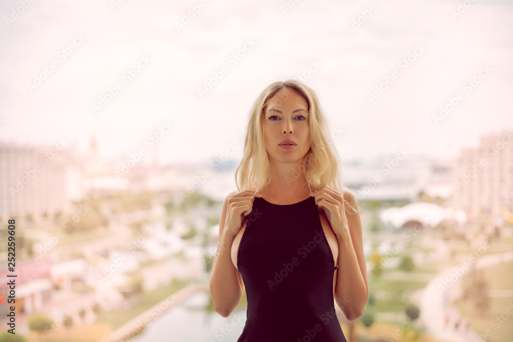 Young beautiful blond fashion woman wearing sexy black dress with open back