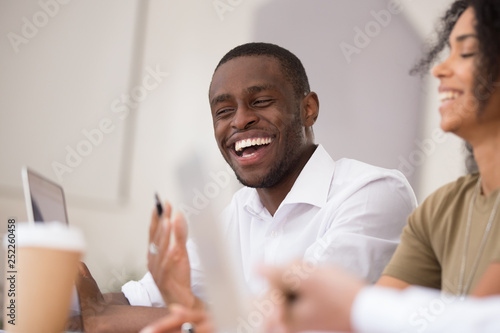 Happy african businessman laughing talking working together with friendly colleagues