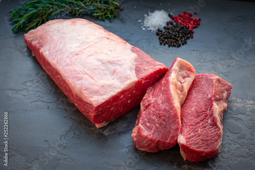 Foto A whole piece of Beef Brisket with sliced two steaks on stone background