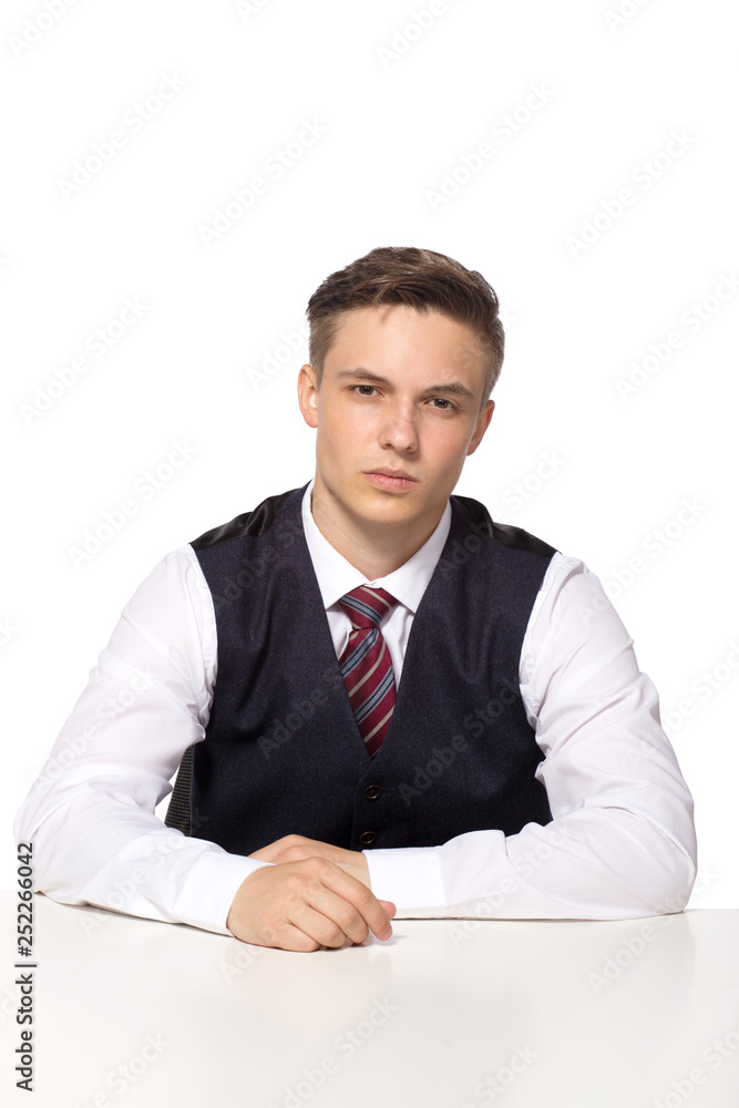 Casual young businessman working in office, sitting at desk, thinking about something, looking at camera Casual young businessman working in office, sitting at desk, thinking about something, looking at camera