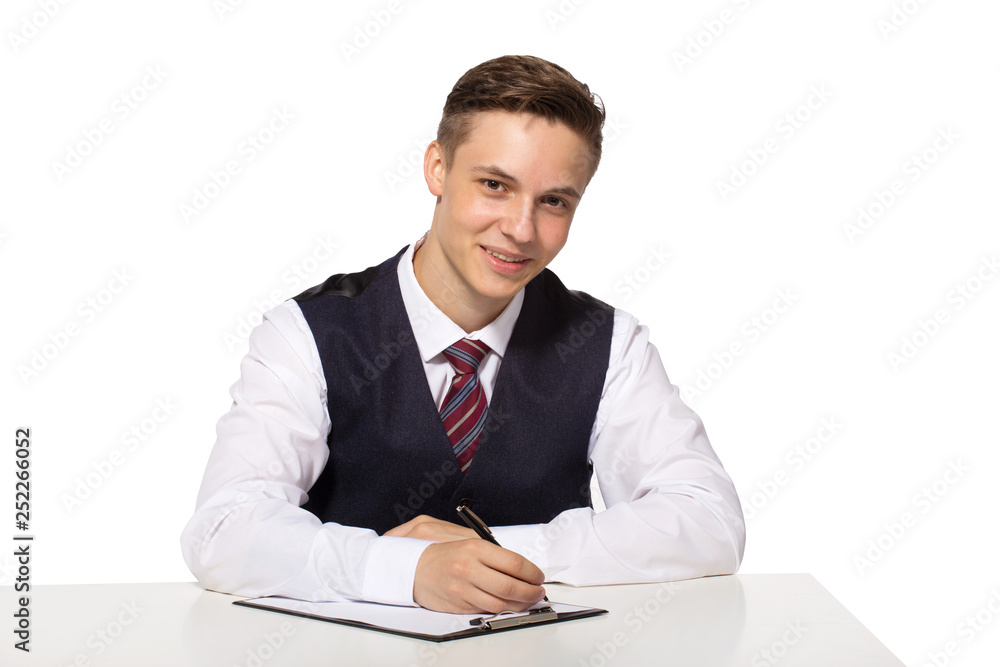 Smiling young businessman working in office, sitting at desk, writing notes to clipboard. Smiling young businessman working in office, sitting at desk, writing notes to clipboard.