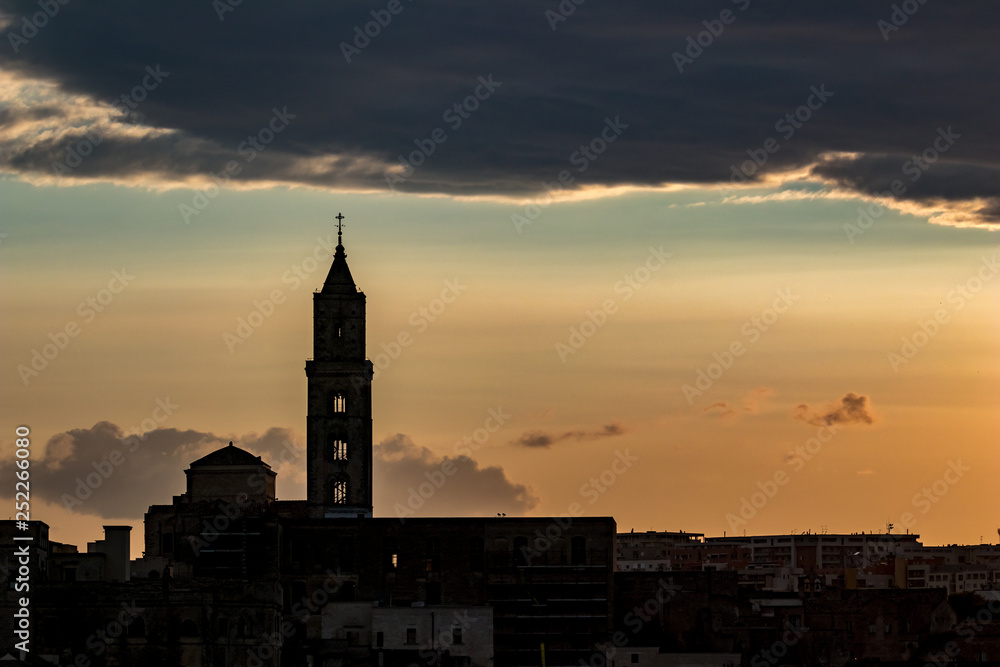 Amazing sky and church silhouette view of ancient town of Matera, the Sassi di Matera, Basilicata, Southern Italy, cloudy summer afternoon just before sunset