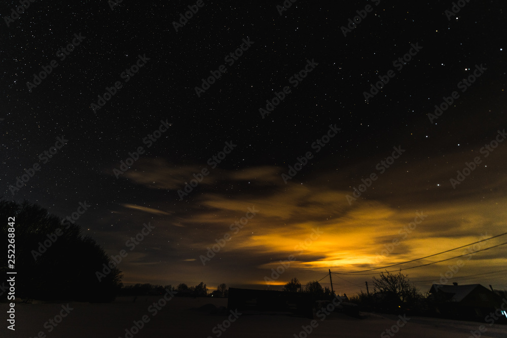 Starry dark sky and yellow light in Carpathian mountains at night in winter