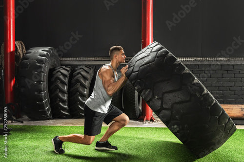 Strong sportsman doing  a tire flip exercise photo