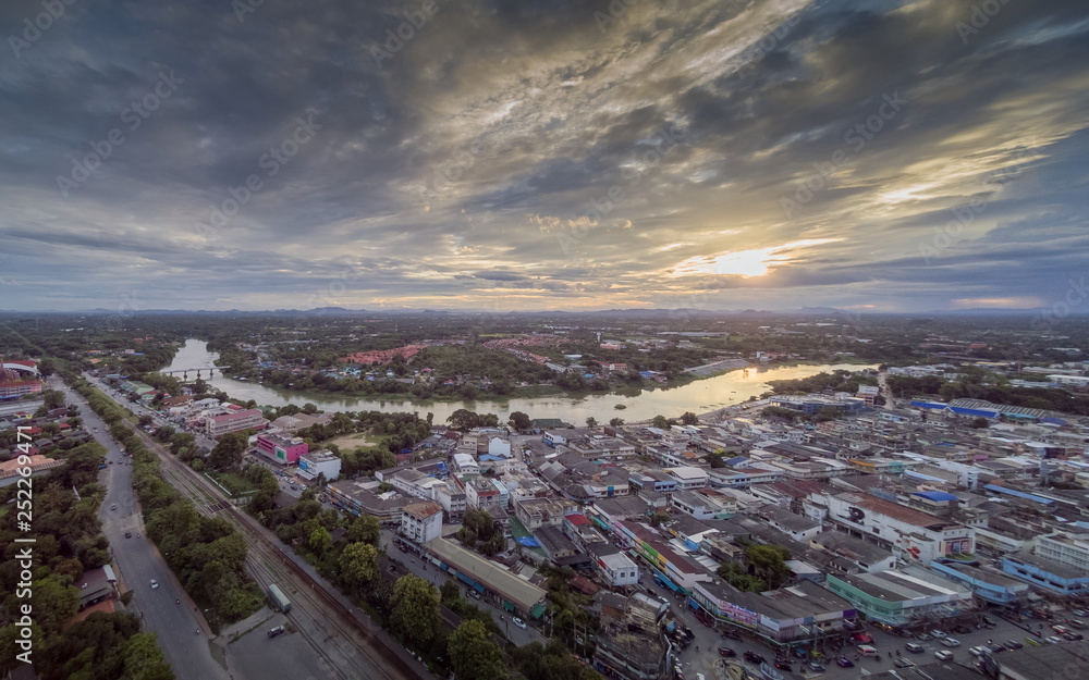 Aerial view above city and Mae Klong river of dark clouds moving with rain storm and sunset background, Ban Pong City, Ratchaburi, Thailand.
