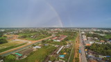 Aerial view above city, houses and village with soft raining and rainbow in the sky background, Ban Pong City, Ratchaburi, Thailand.