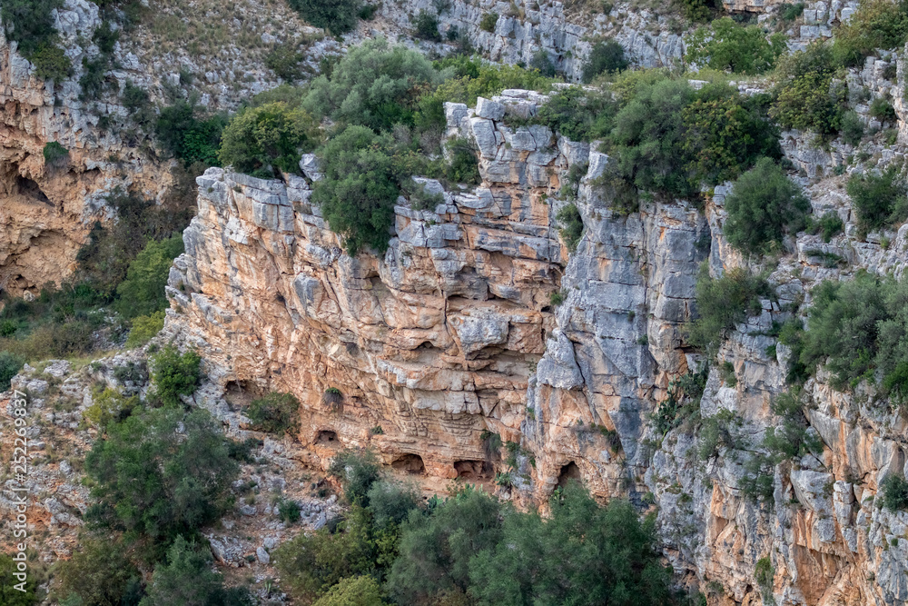 Distant soft colors landscape view of the arched entrances of caves near the ancient town of Matera, the Sassi di Matera, Basilicata, Southern Italy, cloudy summer afternoon just before sunset