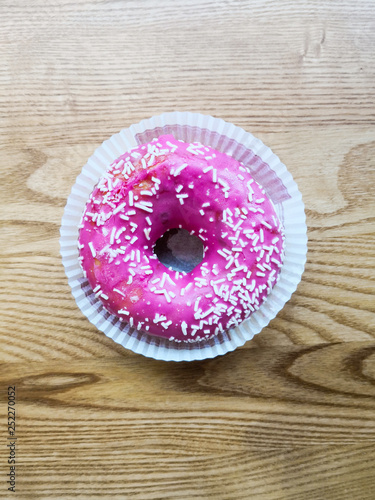 Pink donut with colorful sprinkles isolated on background