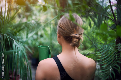 фотографія Portrait of cute young woman holding a rolled yoga mat in jungle