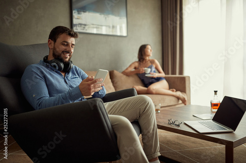 relaxed man using phone while sitting on sofa at his modern home. .
