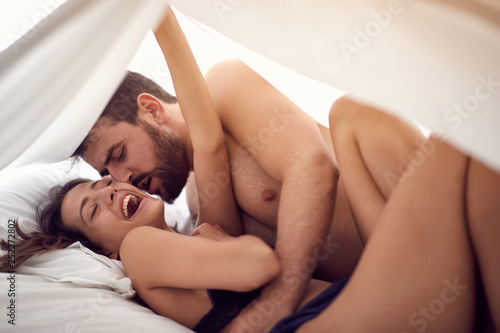 Happy young couple lying and hugging in bed .