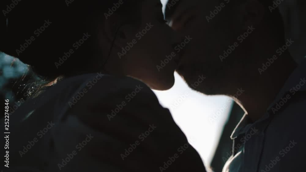 Handsome groom is kissing his charming bride in the forehead at the background of the sunset. Outdoor portrait. Handsome groom is kissing his charming bride in the forehead at the background of the sunset. Outdoor portrait.