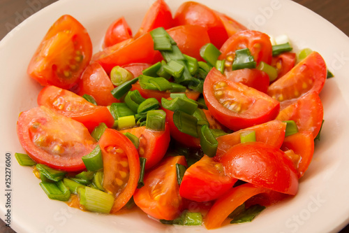 salad of small cherry tomatoes and green onions in a ceramic plate