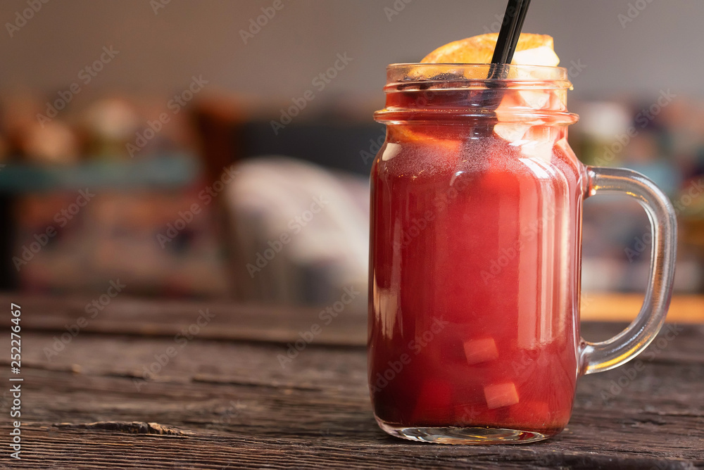 Close up glass jar with hot mulled wine and straw on dark wooden table Close up glass jar with hot mulled wine and straw on dark wooden table