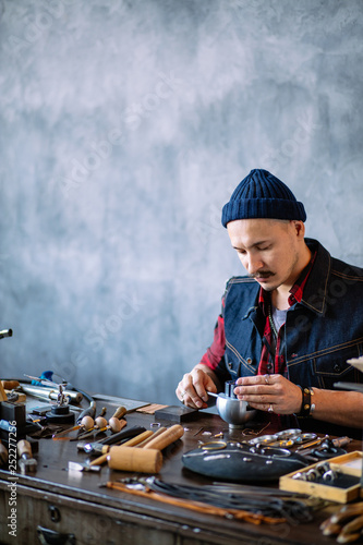close up portrait, young man with moustache making jewelry for customes,engraving tool