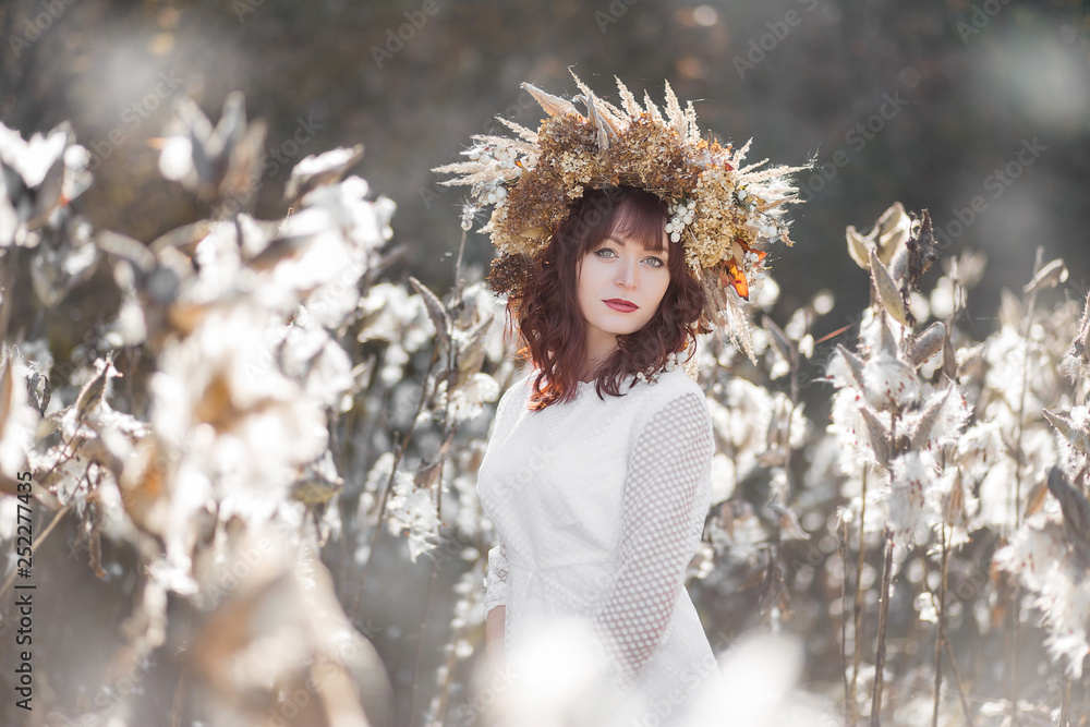 Young beautiful girl in a white vintage dress and wreath of dried ...