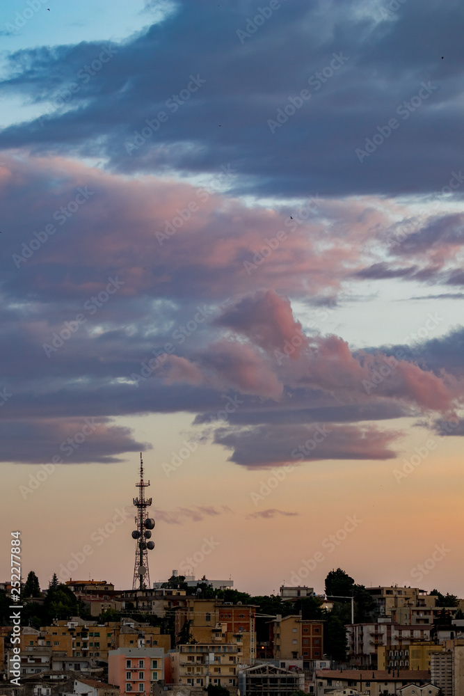 Communication tower against cloudy sunset sky over Matera, the Sassi di Matera, Basilicata, Southern Italy, warm colors scenery summer evening