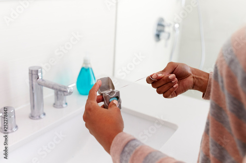 Close Up Of Woman Using Dental Floss From Pack In Bathroom