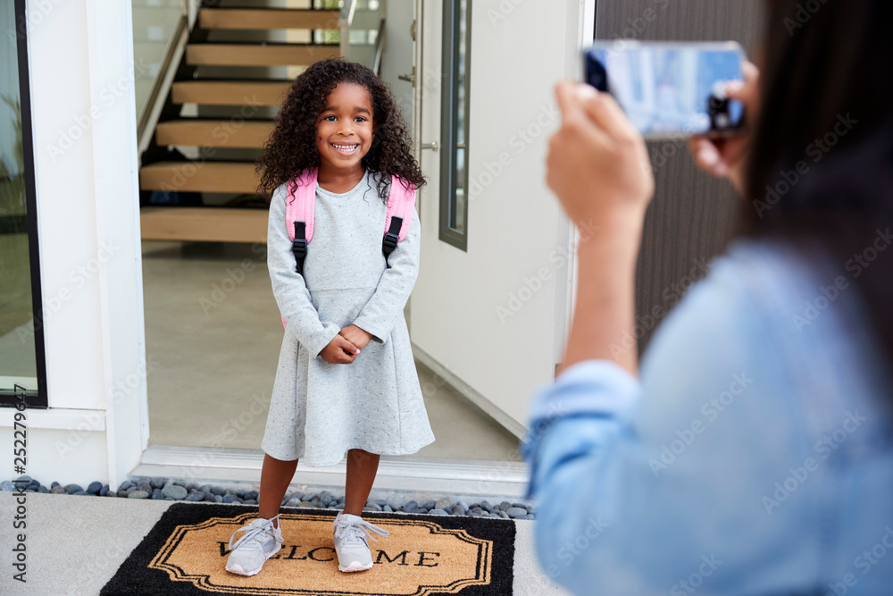 Mother Taking Photo Of Daughter With Cell Phone On First Day Back At School - obrazy, fototapety, plakaty 